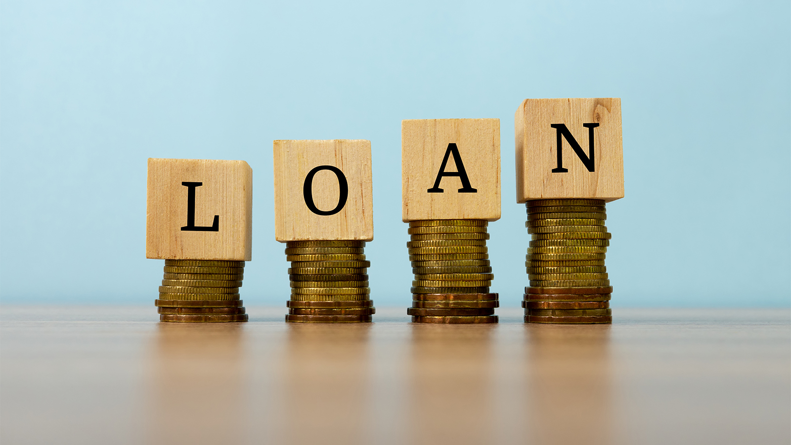 Loan text written on wooden block with stacked coins Business and finance concept